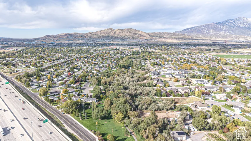 Aerial perspective featuring mountainous horizons, expansive terrain, mature trees, and established neighborhood grounds