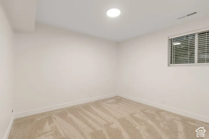 Neutral interior room featuring neutral wall-to-wall carpeting, crisp white walls, and a recessed ceiling light