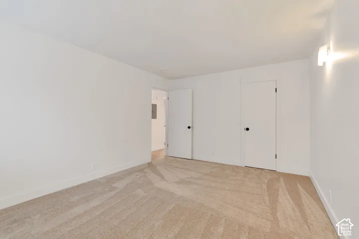 Neutral wall-to-wall carpeting, crisp white interior finishes, solid-core doors with matte black hardware, and wall-mounted light fixture