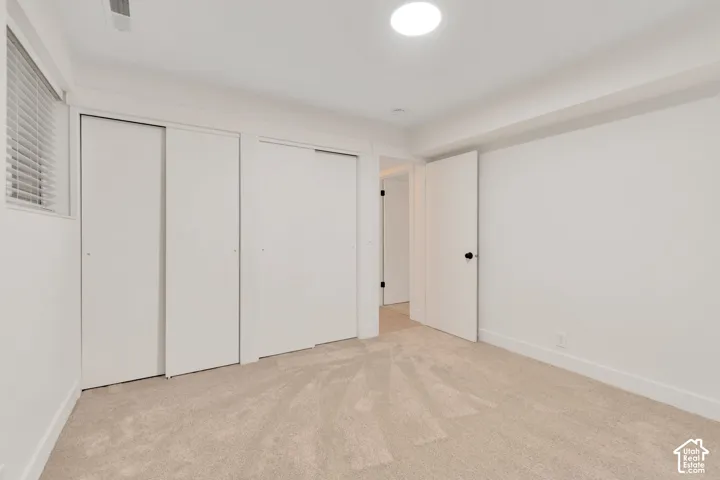 Neutral-toned carpeted flooring, dual sliding-door closets, recessed ceiling lighting, and horizontal window blinds