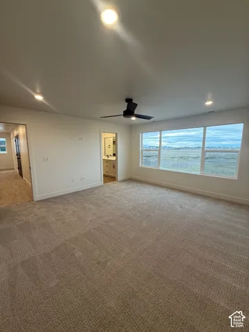 Neutral-toned carpeting, matte black ceiling fan, recessed lighting, and expansive windows framing the horizon