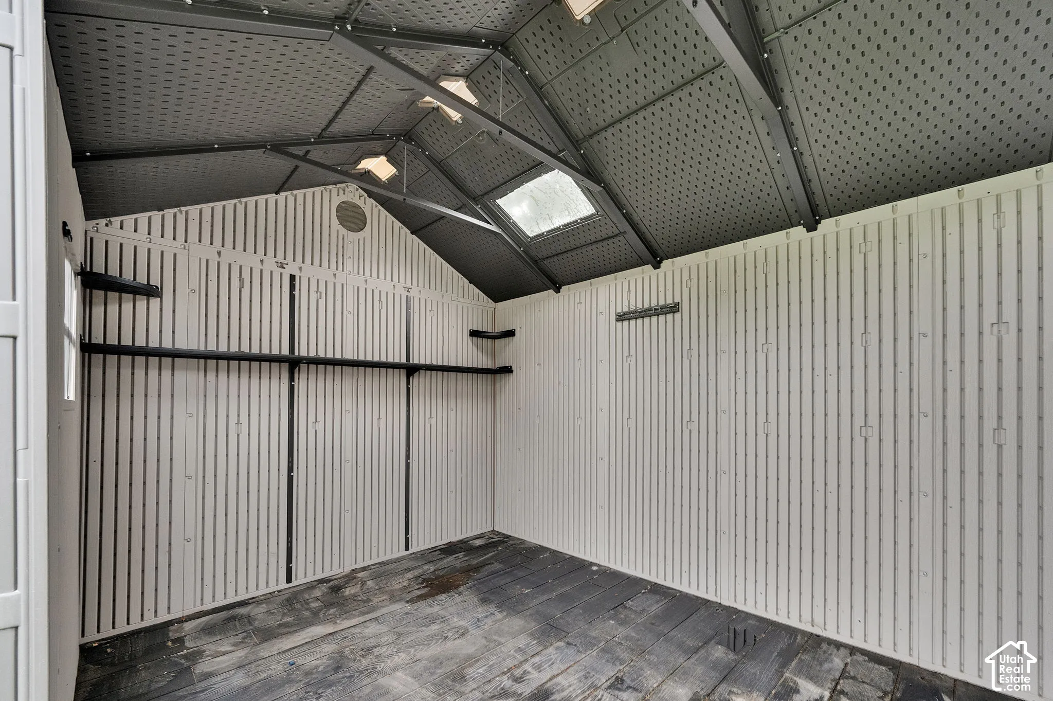 Storage structure featuring high-vaulted ceilings, integrated skylights, reinforced steel framing, built-in shelving, and vertical-panel wall construction