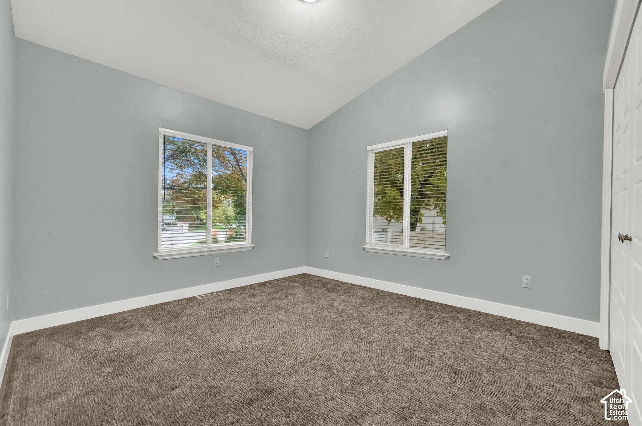 Vaulted ceilings, neutral wall color, wall-to-wall carpeting, dual windows, and paneled closet doors