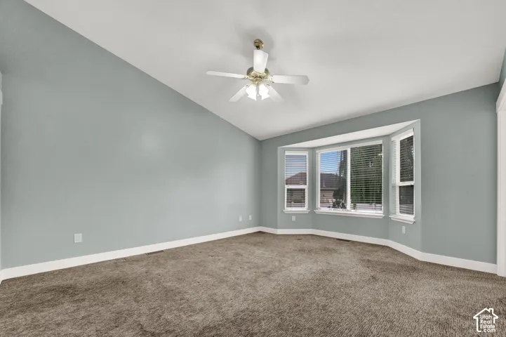 Vaulted ceiling featuring a central multi-blade ceiling fan with integrated lighting and a prominent bay window configuration
