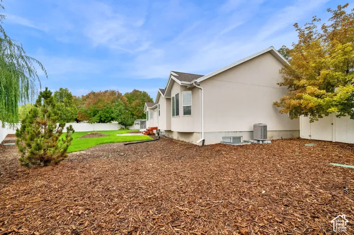 Exterior featuring a multi-gabled roofline, light-toned siding, white vinyl perimeter fencing, and a mulched ground cover