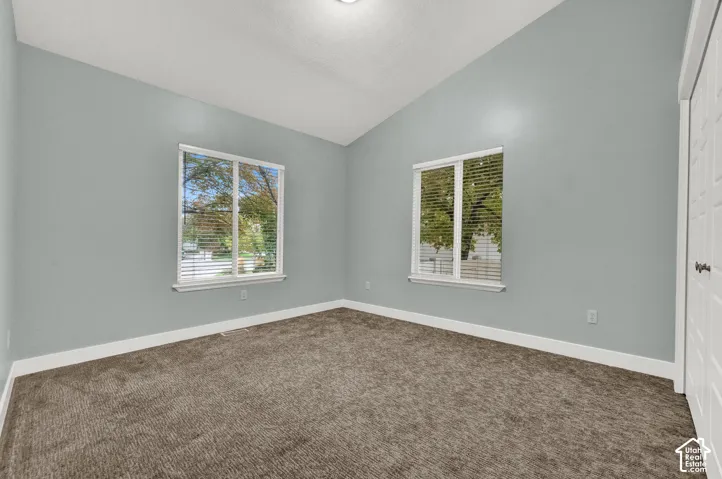 Vaulted ceilings, neutral wall color, wall-to-wall carpeting, dual windows, and paneled closet doors