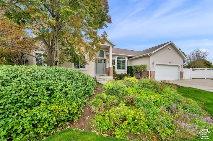 Stucco exterior featuring an arched entryway, stone veneer accents, multi-pane windows, and an attached two-car garage