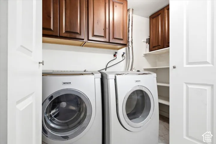 Laundry closet featuring medium-tone wood cabinetry, white open shelving, and double-panel doors