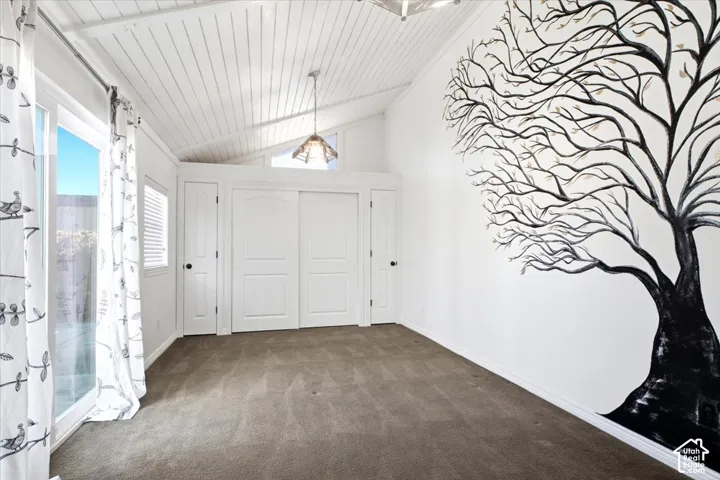 Vaulted ceiling featuring white beadboard paneling, sliding glass door, built-in closet cabinetry, and geometric metal pendant lighting