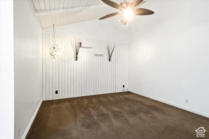Vaulted ceiling with exposed wood-plank detailing, vertical shiplap accent wall, built-in wall shelving, and a ceiling fan with integrated lighting