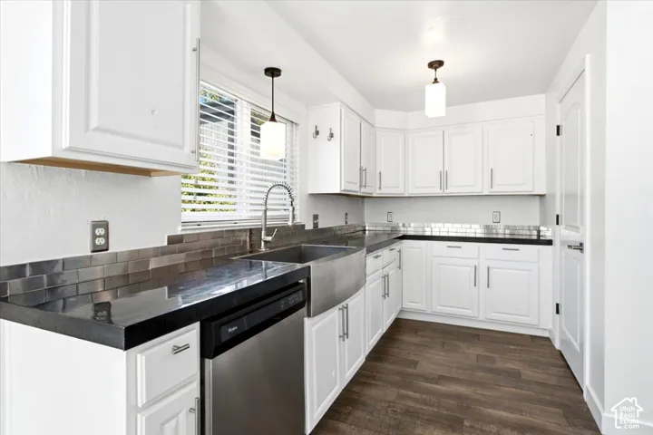 Kitchen featuring white shaker-style cabinetry, dark stone countertops, metallic subway tile backsplash, stainless steel farmhouse sink, and wood-finish flooring