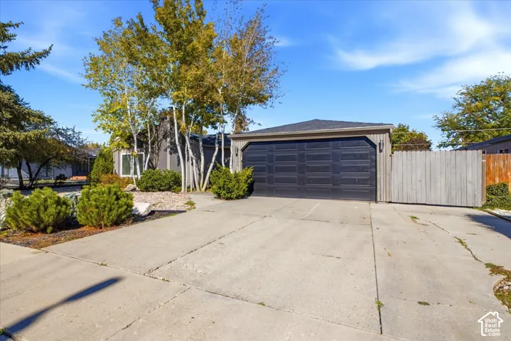 Detached garage with a multi-panel door, concrete driveway, and wood-panel privacy fencing