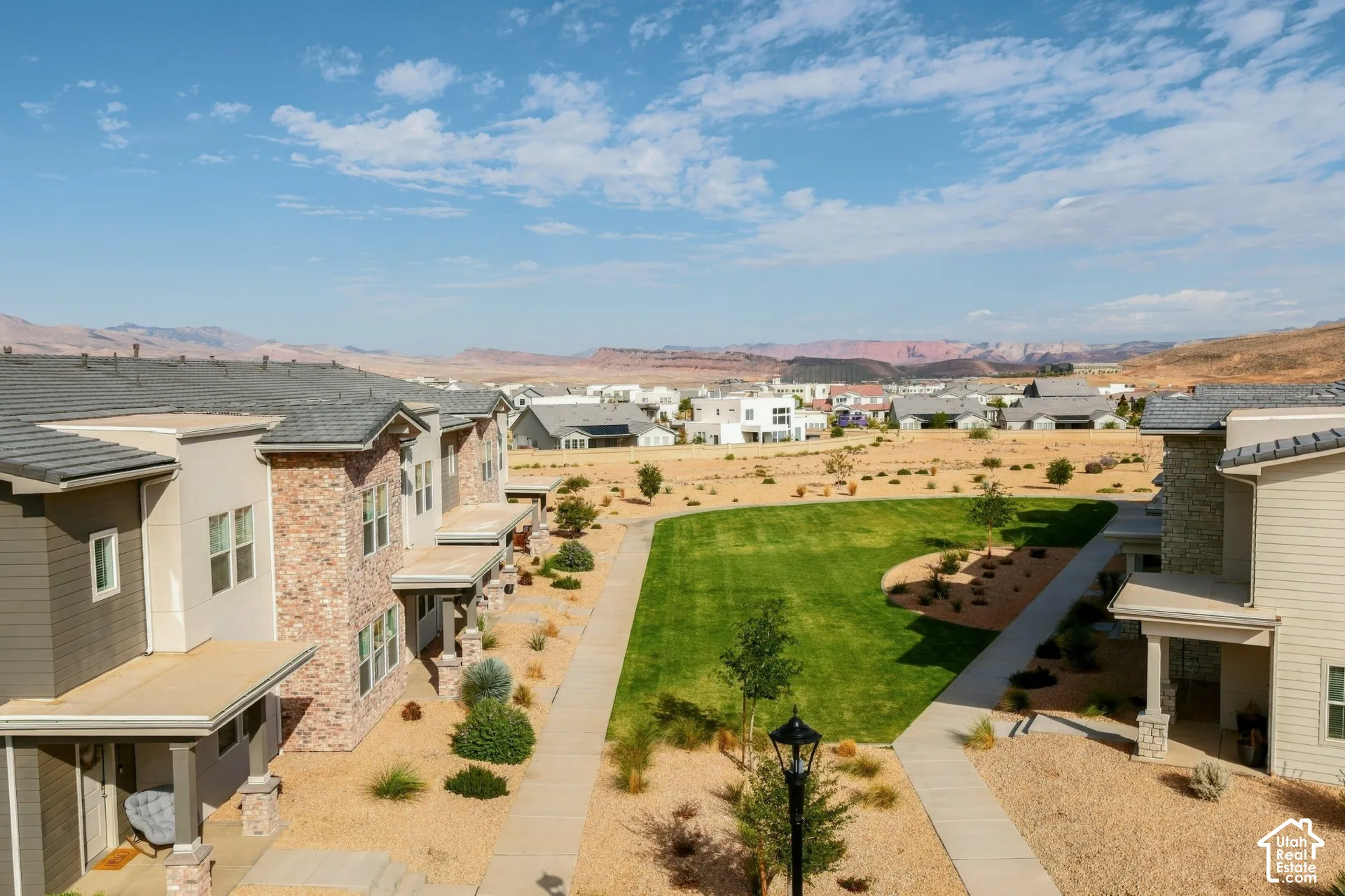 Multi-story residential exteriors featuring stone veneer and stucco siding, private covered entry porches, concrete walkways, and an expansive lawn area with xeriscape landscaping