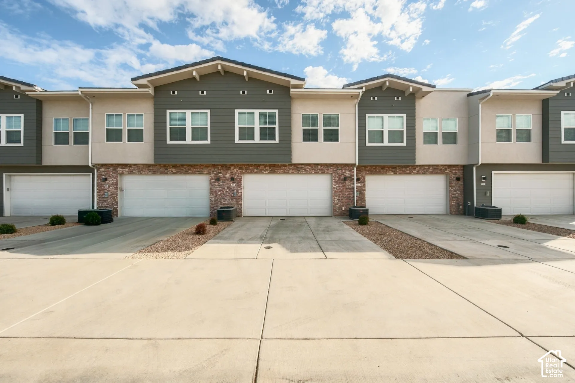 Multi-unit exterior featuring stone veneer siding, horizontal lap siding, and attached multi-car garages with concrete driveways
