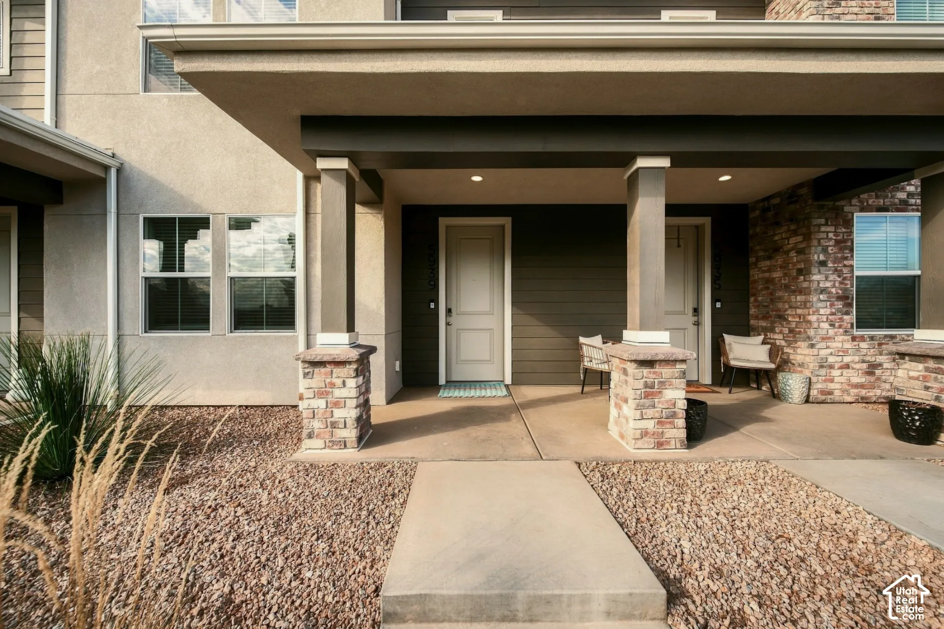 Covered entryway featuring horizontal siding, brick-veneer pillar bases, concrete walkway, and recessed lighting