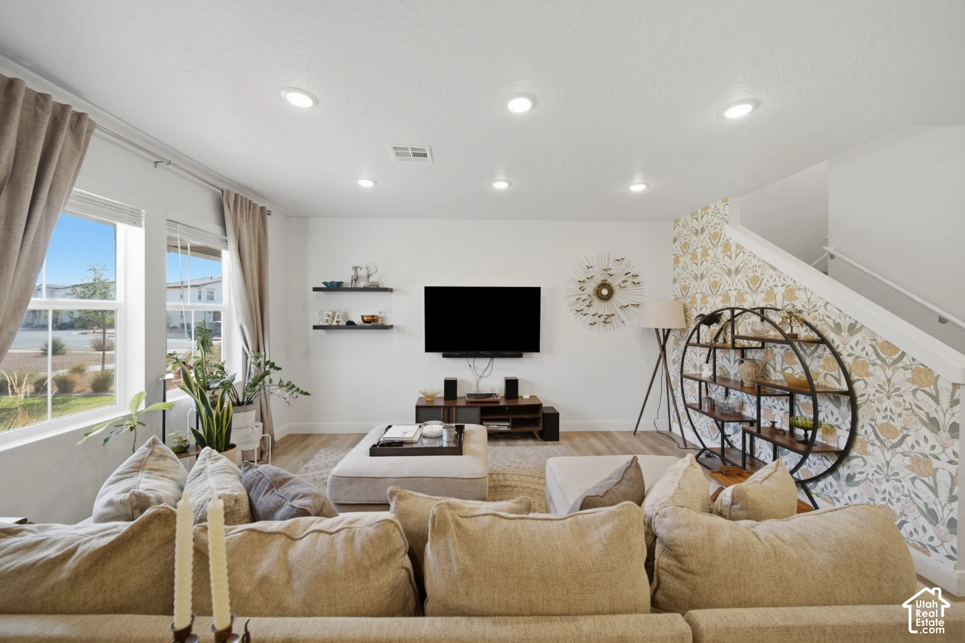 Living area featuring recessed lighting, wood-finish flooring, two floating shelves, and an accent wall with patterned wallpaper