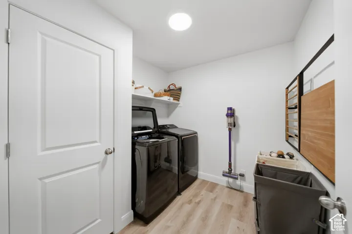Laundry space featuring wood-finish flooring, a ceiling-mounted light fixture, and an overhead built-in shelving unit