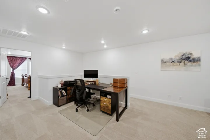 Open room featuring neutral carpeting, recessed ceiling lighting, and a half-wall partition with a ledge