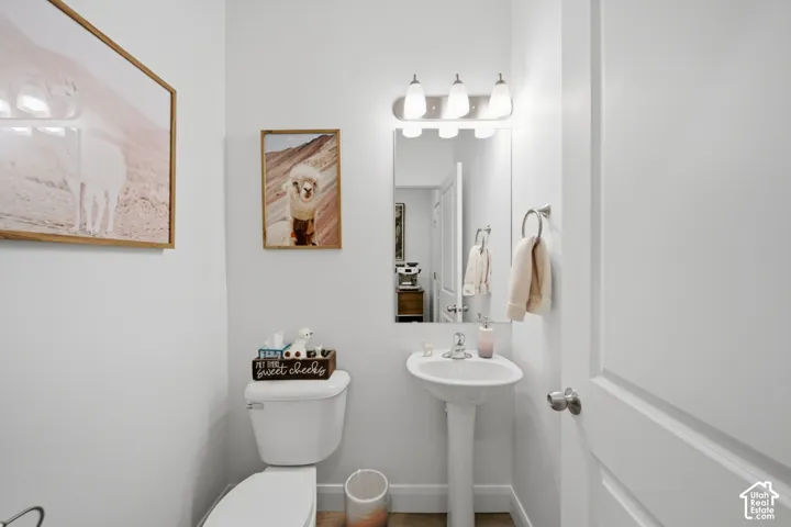 Pedestal sink with a single-handle faucet, wall-mounted three-light fixture, and rectangular mirror