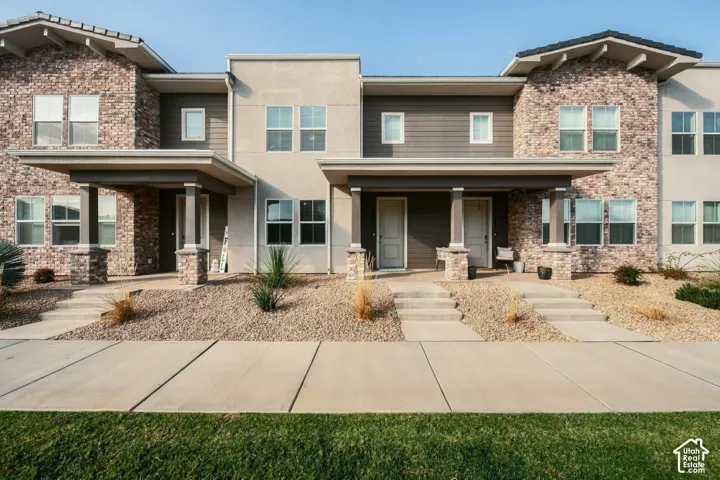 Exterior facade featuring mixed-material construction of brick masonry, smooth stucco, and horizontal siding, accented by covered entry porches with stone-clad pillars and dual-tone detailing