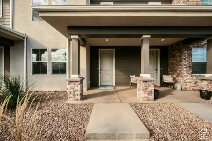 Covered entryway featuring horizontal siding, brick-veneer pillar bases, concrete walkway, and recessed lighting