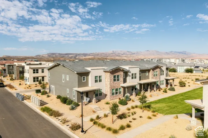 Multi-unit building exterior featuring horizontal siding and masonry veneer accents, covered entryway porches with stone columns, and mountain scenery
