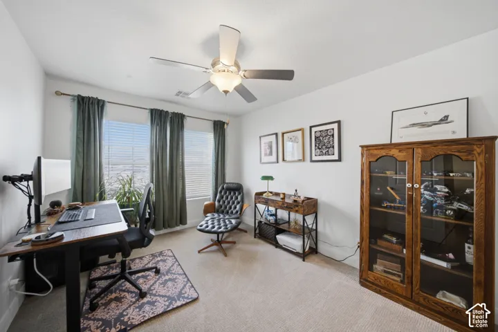 Neutral interior featuring light-toned carpeting, dual windows with horizontal blinds, and a ceiling-mounted light fixture with a fan