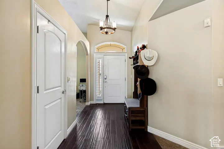 Entryway featuring dark wood-finish flooring, a decorative chandelier, an arched doorway, and a front door with a transom window