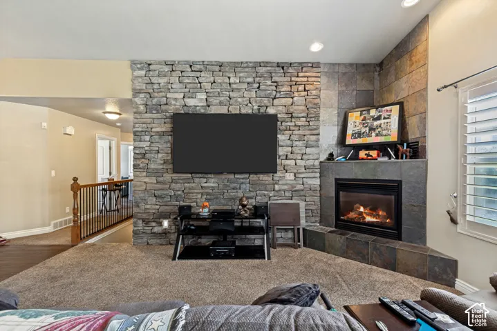 Stone accent wall, gas fireplace with stone surround, recessed lighting, wood railing, and window with white shutters