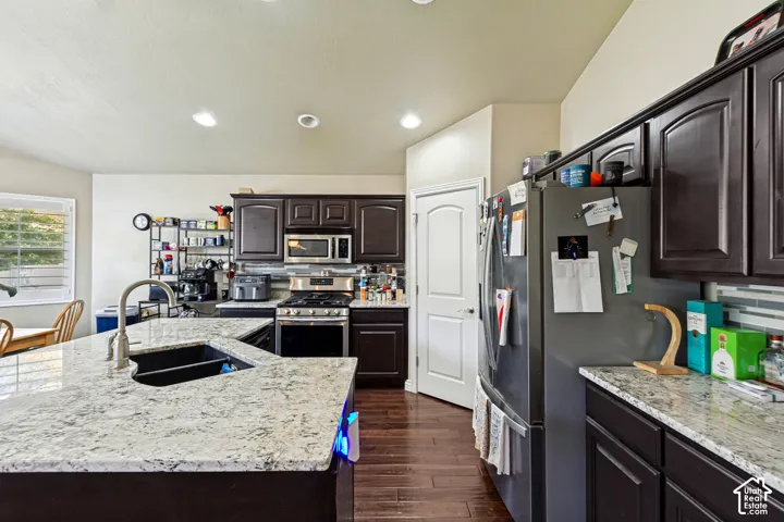 Kitchen featuring rich wood-finish cabinetry, light-toned countertops, a stainless steel range, and a deep basin sink with a gooseneck faucet