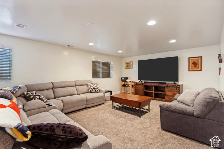 Carpeted room with recessed lighting, two windows with horizontal blinds, and a built-in media console