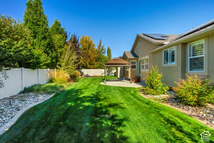 Expansive lawn with perimeter landscaping, a privacy fence, and an exterior patio