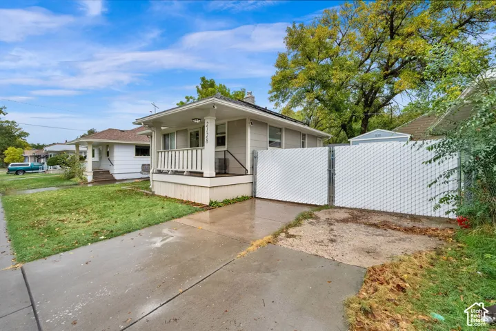 Single-story residence featuring horizontal siding, a covered front porch with white railing, and a privacy-fenced exterior area