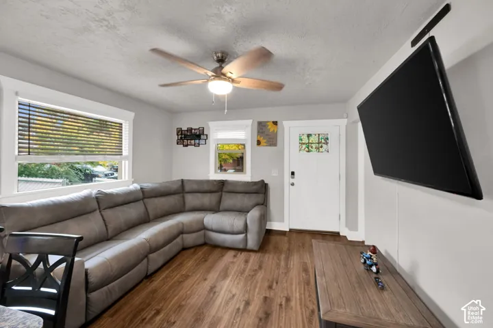 Wood-finish flooring, ceiling fan with integrated lighting, multipane window casing, and exterior door with decorative glass inlay