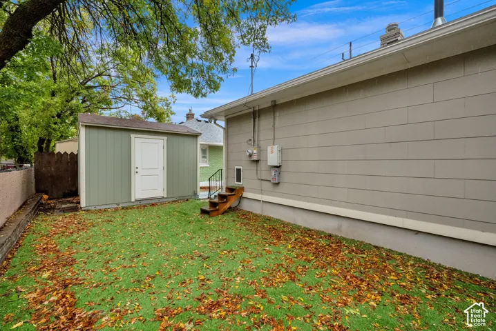 Exterior backyard space featuring horizontal siding, a detached storage shed, wood-framed stairs, and mature trees