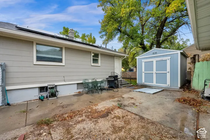 Exterior featuring horizontal lap siding, concrete patio, detached storage shed, and roof-mounted solar panels