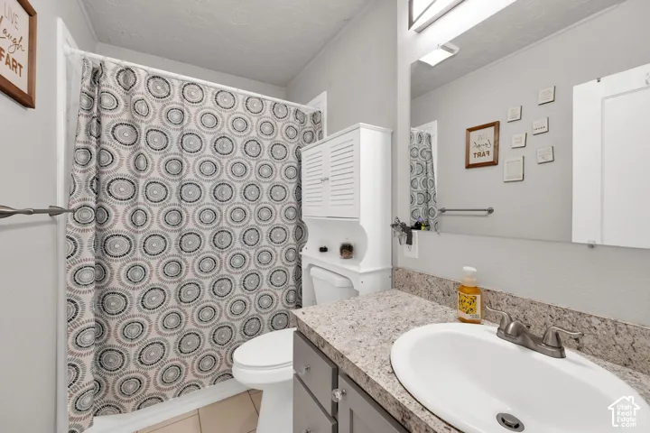 Bathroom featuring a stone-look countertop, integrated oval sink, matte finish plumbing fixtures, and a large-format mirror with integrated lighting