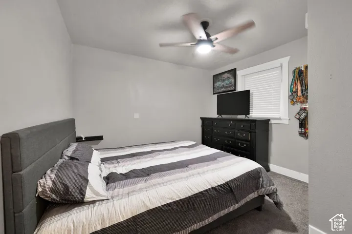 Neutral wall-toned room featuring plush carpeting, a ceiling fan with integrated lighting, and window blinds