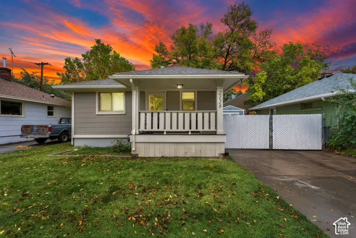 Single-story exterior featuring a covered front porch, horizontal siding, asphalt shingle roof, and a privacy gate