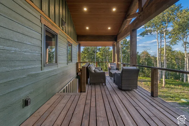 Expansive covered deck featuring wood-finish flooring, exposed wood beams, and recessed lighting