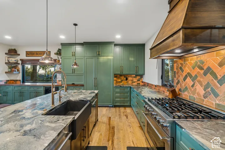 Central island with a dark basin sink, rich wood flooring, vibrant green cabinetry, and a herringbone pattern tile backsplash