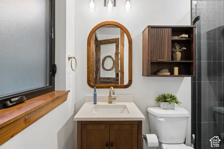 Single vanity with a light-toned countertop, wood-finish cabinetry, and a framed mirror