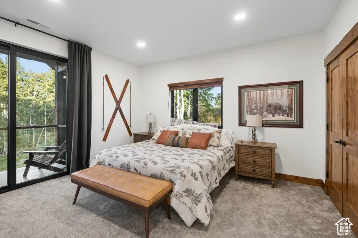 Sliding glass door leading to an outdoor space, wood-finish door, wood-finish window trim, recessed lighting, and carpeted flooring