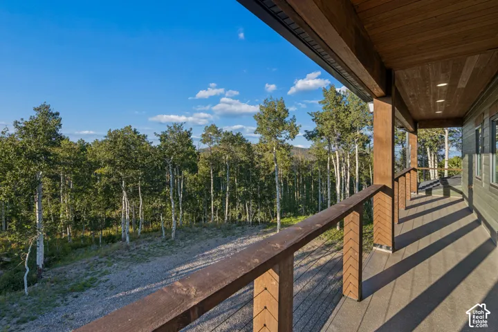 Covered outdoor patio with a wood-plank ceiling, recessed lighting, and a wood-finish railing with cable infill