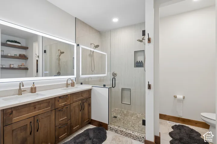 Double vanity with undermount sinks, illuminated mirrors, and wood-finish cabinetry