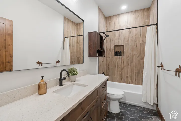 Vanity with integrated sink, light-toned countertop, wood-finish cabinetry, and black-framed mirror