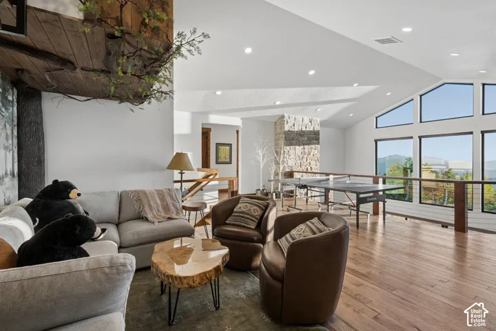 Vaulted ceilings, expansive windows, recessed lighting, wood-finish flooring, and a stone-clad column