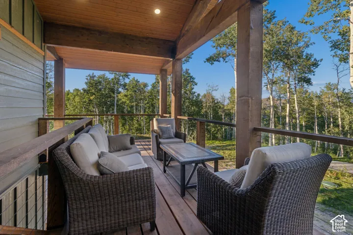 Covered deck featuring wood plank flooring, wood support beams, and cable railings
