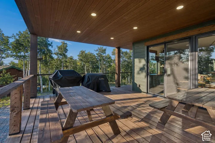 Expansive covered deck with wood-finish flooring, recessed lighting, and large sliding glass doors