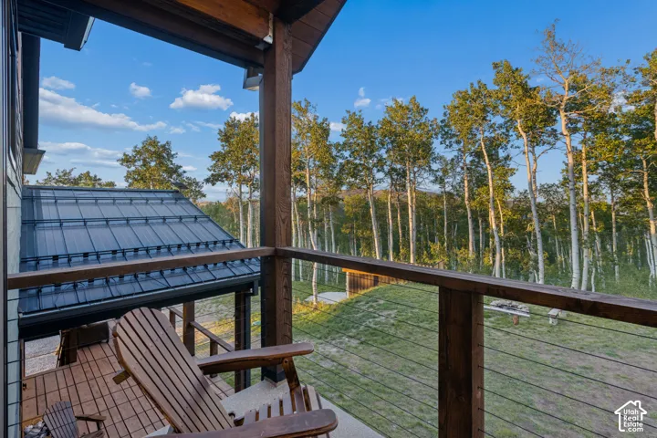 Wood-finish deck with cable railing, surrounded by mature trees